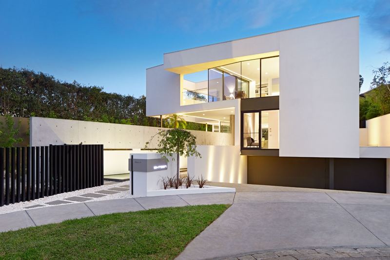 NQ Build custom home exterior at twilight — pool, glass pavilion and landscaped garden